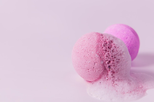 Bombas de baño coloridas humeando en una superficie rosa claro en una atmósfera relajante