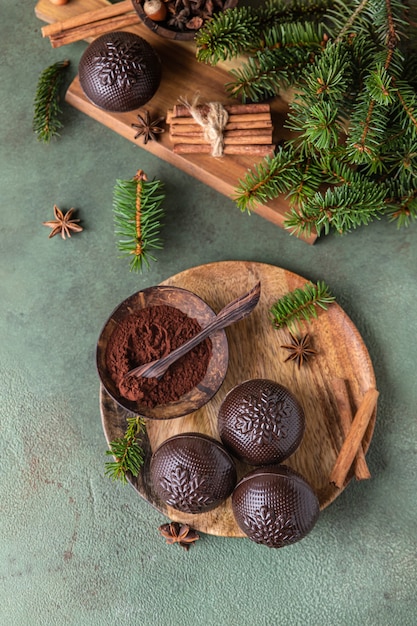 Bombas de cacao sabroso con malvavisco y chocolate en placa de madera con ramas de abeto y especias