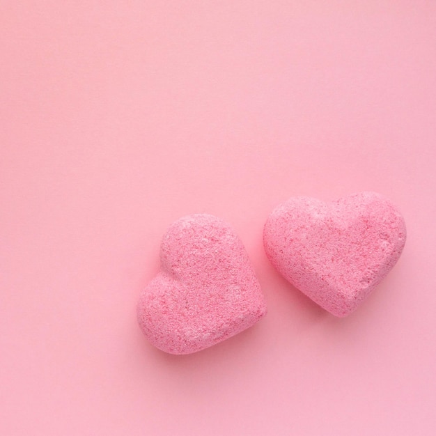 Bombas de banho em forma de coração no fundo rosa, vista superior.