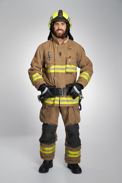 Foto bombeiro barbudo sorridente em uniforme protetor posando no estúdio vista frontal de homem caucasiano feliz