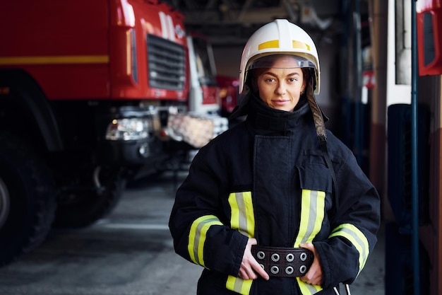 Bombeiro feminino em uniforme de proteção em pé perto de caminhão