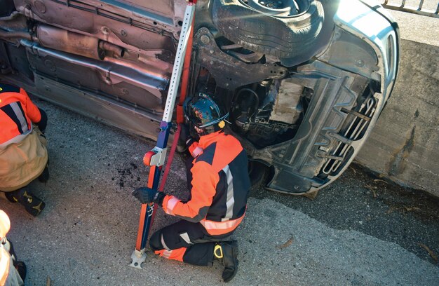 Bombeiro na frente de um carro batido tentando resgatar uma vítima