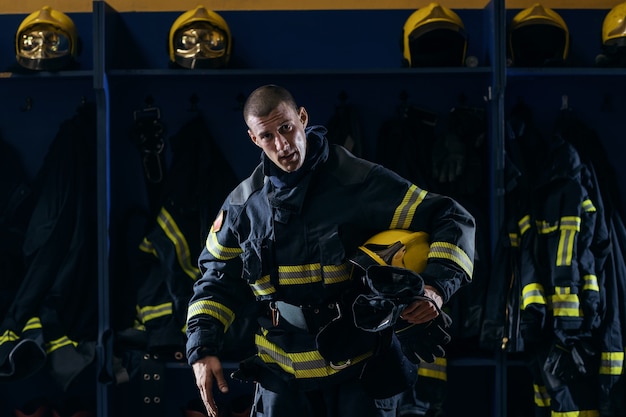 Bombeiro segurando o capacete sob a axila após a ação em pé no corpo de bombeiros.