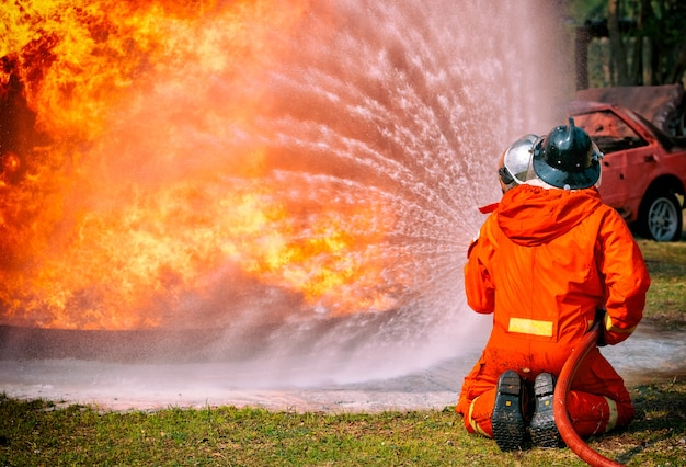 Bombeiros de água pulverizada pelo bocal de alta pressão em fogo