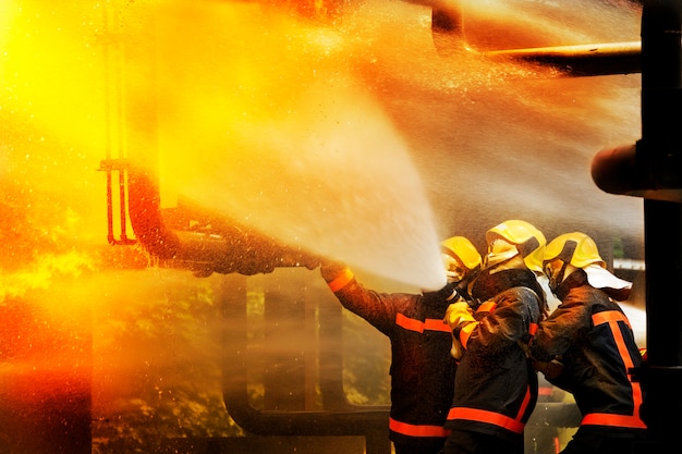 Foto bombeiros que usam o extintor e a água para o fogo do lutador durante o treinamento do firefight.