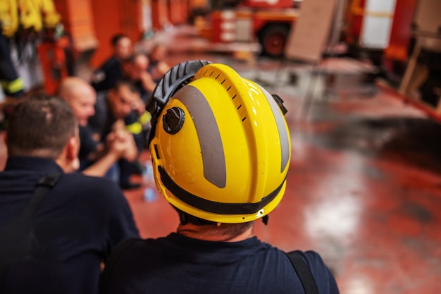 Foto bombeiros sentados em círculo e fazendo uma pausa do dia difícil.