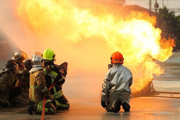Bombeiros usando extintor de incêndio tipo neblina de água Twirl para lutar com a chama de fogo do óleo para controlar o fogo para não espalhar o conceito de bombeiro e segurança industrial