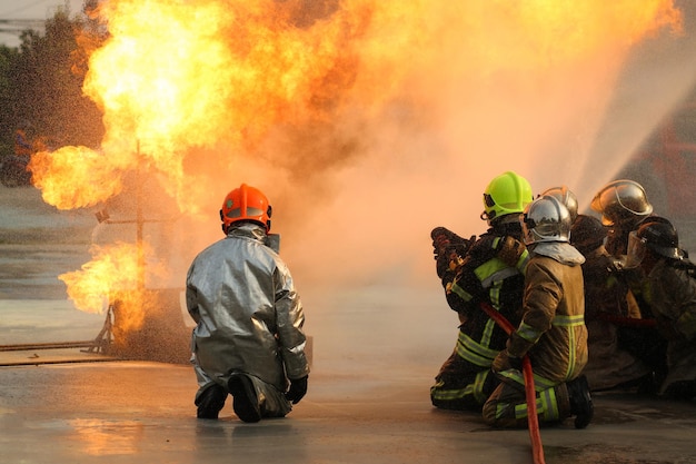 Bombeiros usando extintor de incêndio tipo neblina de água twirl para lutar com a chama de fogo do óleo para controlar o fogo para não espalhar o conceito de bombeiro e segurança industrial