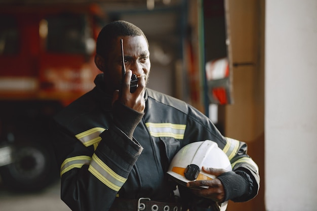 Bombero de Arfican en uniforme. El hombre se prepara para trabajar. Guy usa transmisor de radio.