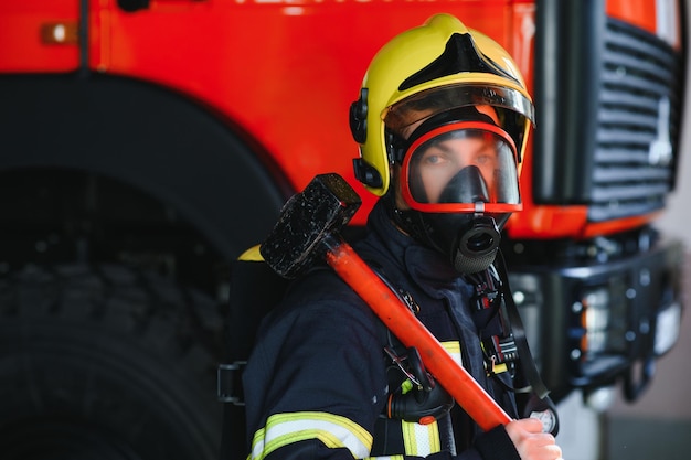 Bombero bombero en acción de pie cerca de un camión de bomberos Seguridad de emergencia Rescate de protección del peligro