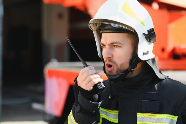 Bombero bombero en acción de pie cerca de un camión de bomberos Seguridad de emergencia Rescate de protección del peligro