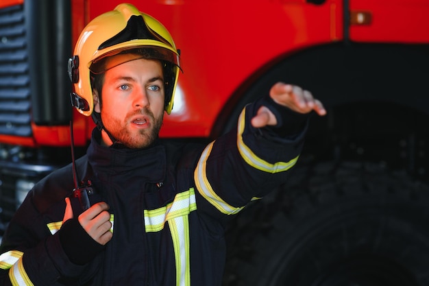 Foto bombero bombero en acción de pie cerca de un camión de bomberos seguridad de emergencia rescate de protección del peligro