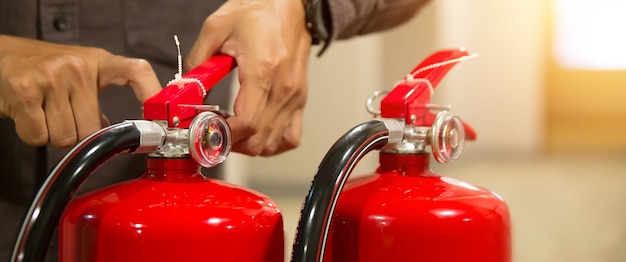Foto bombero comprobando el pasador de seguridad en el mango del extintor.