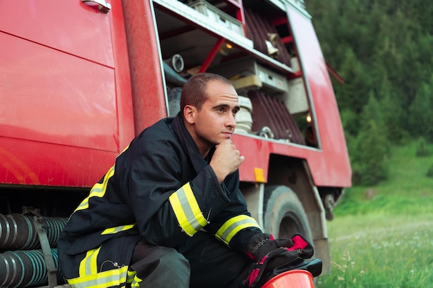 bombero deprimido y cansado cerca del camión de bomberos. foto de alta calidad