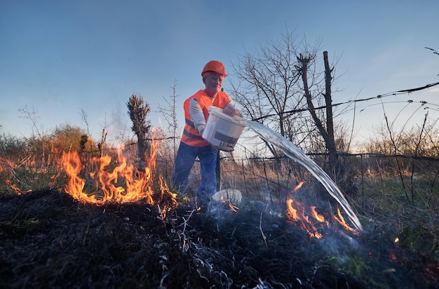 Foto bombero ecologista luchando contra el fuego en el campo por la noche