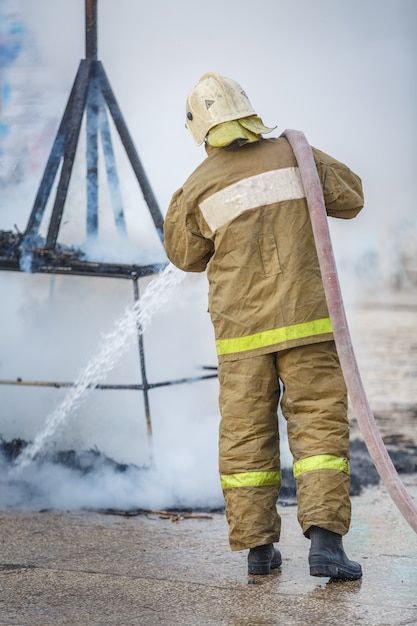 Un bombero extingue los restos de fuego en el humo.