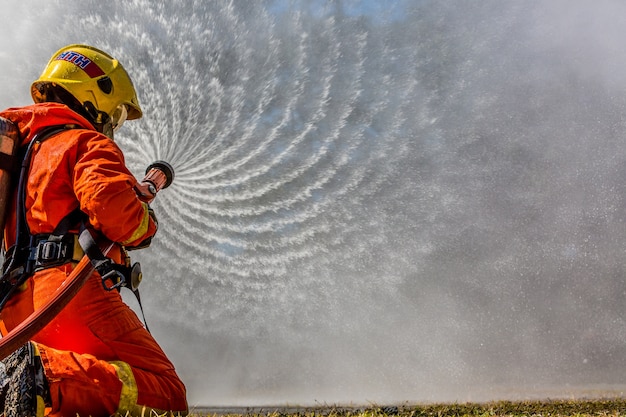 Foto bombero con extintor y agua de la manguera para la extinción de incendios