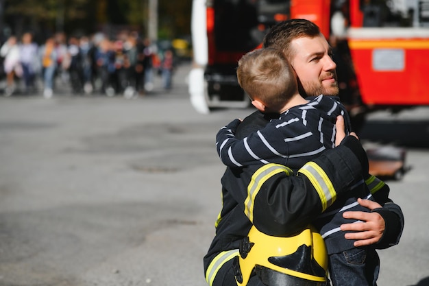 Bombero sosteniendo a un niño para salvarlo del fuego y el humoLos bomberos rescatan a los niños del fuego