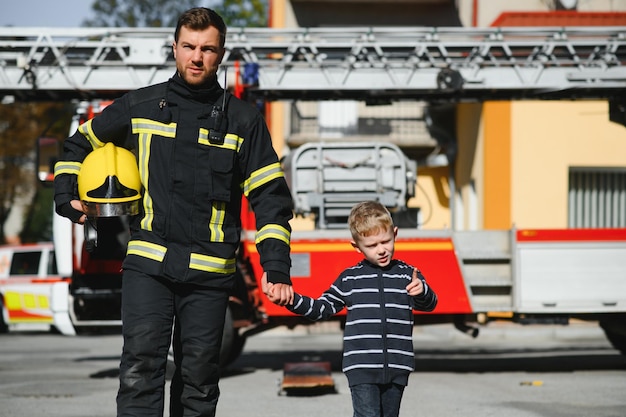 Bombero sosteniendo a un niño para salvarlo del fuego y el humoLos bomberos rescatan a los niños del fuego