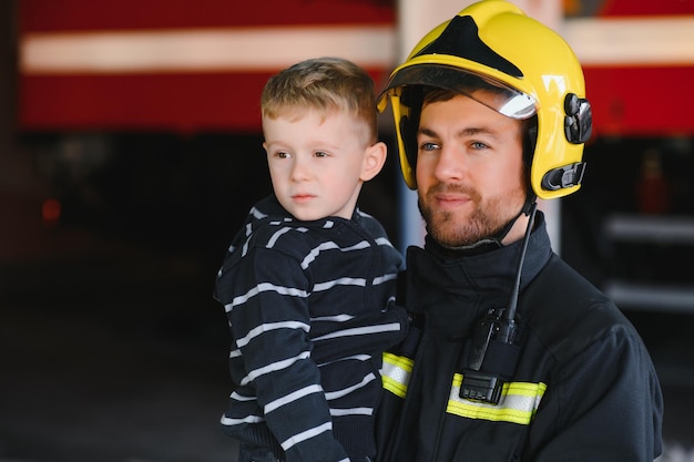 Bombero sosteniendo a un niño para salvarlo del fuego y el humoLos bomberos rescatan a los niños del fuego