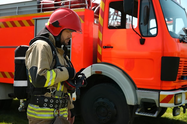 Bombero en uniforme cerca de un camión de bomberos al aire libre