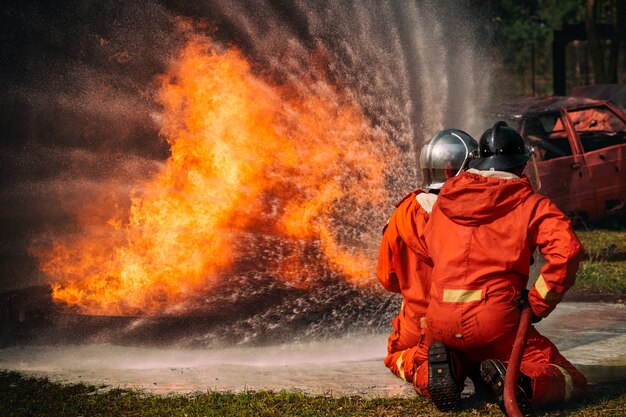 Foto bomberos agua pulverizada por boquilla de alta presión en el fuego