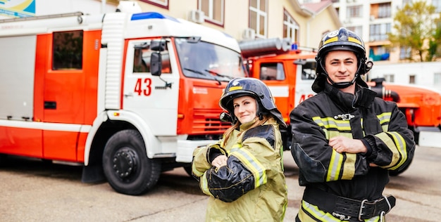 Bomberos mujer y hombre en cascos cerca de camión de bomberos Rescate de protección del peligro Estación de bomberos