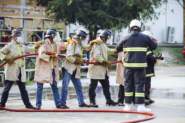 Foto bomberos que usan el extintor de incendios tipo niebla de agua twirl para luchar con la llama del aceite para controlar el fuego y no extender el concepto de bombero y seguridad industrial