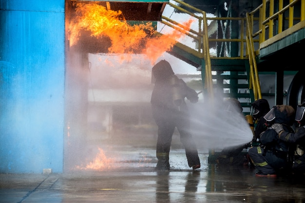 Bomberos usando agua de la manguera para la extinción de incendios en la formación de fuego del grupo de seguros