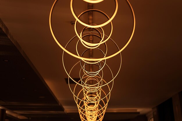 La bombilla colgante borrosa en forma de anillos desdibuja la hermosa iluminación abstracta bajo el techo de las modernas lámparas redondas de electricidad colgante araña de luces amarillas doradas brillantes dentro de una habitación