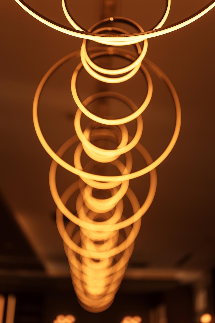Foto la bombilla colgante borrosa en forma de anillos desdibuja la hermosa iluminación abstracta bajo el techo de las modernas lámparas redondas de electricidad colgante araña de luces amarillas doradas brillantes dentro de una habitación
