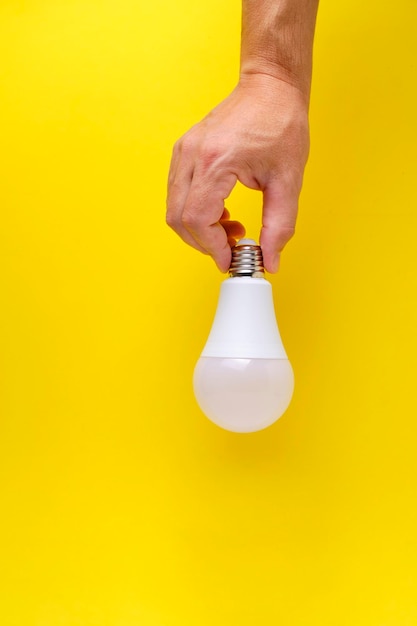 Bombilla LED ecológica en mano sobre fondo amarillo