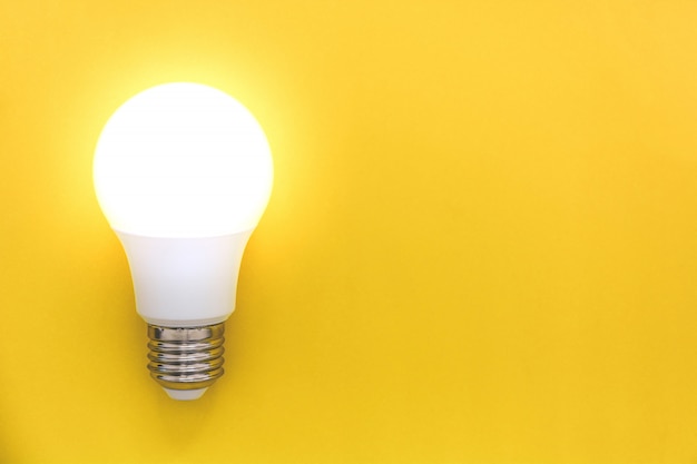 Bombilla LED sobre fondo amarillo, concepto de ideas, creatividad, innovación o ahorro de energía, espacio de copia, vista superior, plano