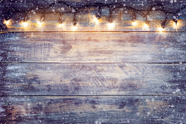 Bombilla de luces de Navidad con nieve sobre la mesa de madera. Feliz Navidad (Navidad) de fondo. topview, diseño de la frontera - estilos rústicos y del vintage