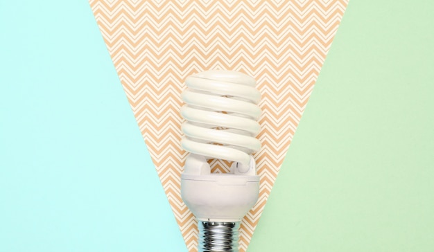Bombilla de luz de ahorro de energía en espiral sobre fondo de papel pastel. Vista superior