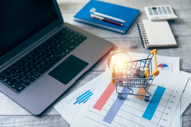 Bombilla de luz en la cesta de la compra con portátil
