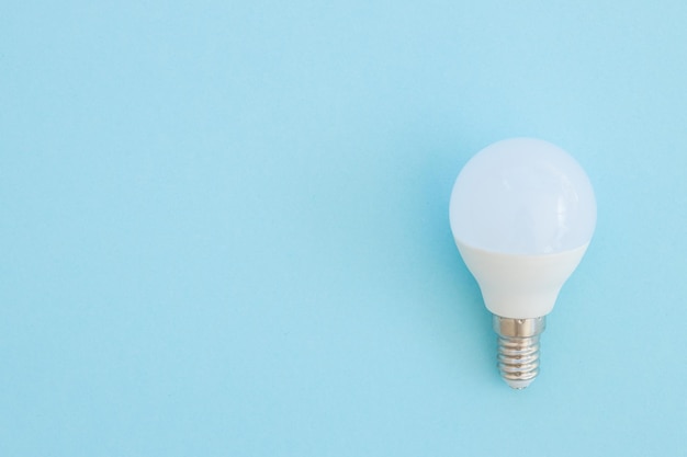 La bombilla de luz LED se encuentra sobre un fondo azul pastel Concepto de ahorro de energía Vista superior minimalista