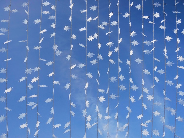 Bombillas de luz de Navidad formas de copos de nieve contra el cielo azul