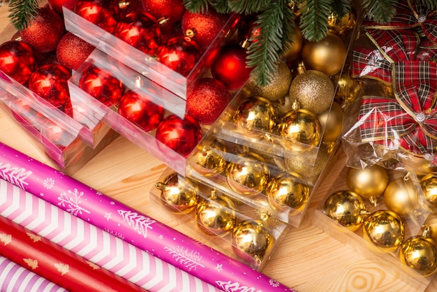 Bombillas de Navidad doradas y rojas envolviendo arcos de papel sobre fondo de madera Preparando adornos navideños para la temporada de vacaciones