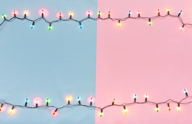 Foto las bombillas de navidad se encendieron o la tapa de la cuerda en colores sobre el backgrou rosa y azul