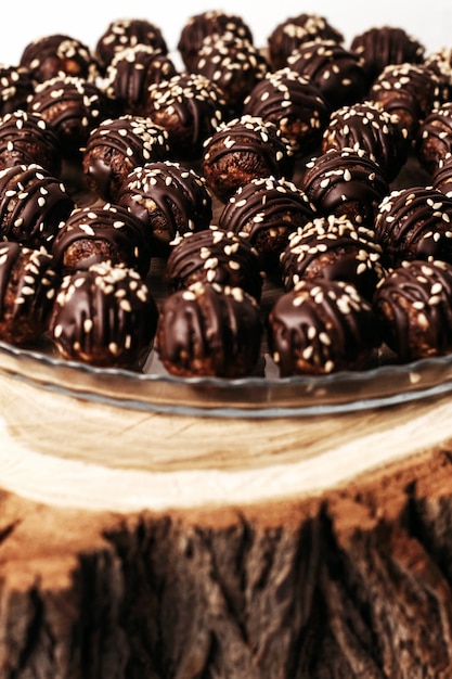 Bombom de chocolate redondo com sementes de gergelim. fundo escuro, sobremesa de luxo, chocolate escuro, feito à mão.