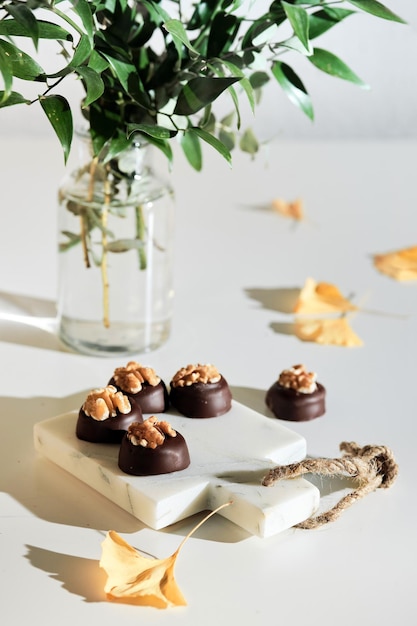 Bombones de chocolate con nueces en la tabla de cortar de mármol closeup en arreglo de otoño de dulces