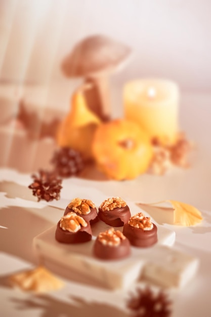 Bombones de chocolate con nueces en la tabla de cortar de mármol closeup en arreglo de otoño de dulces