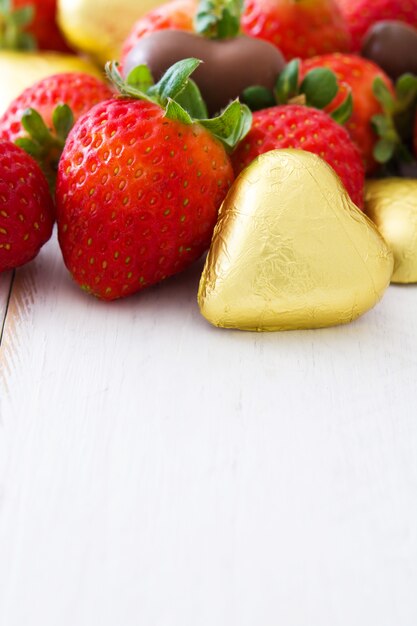 Bombones de fresas y chocolate en mesa de madera blanca