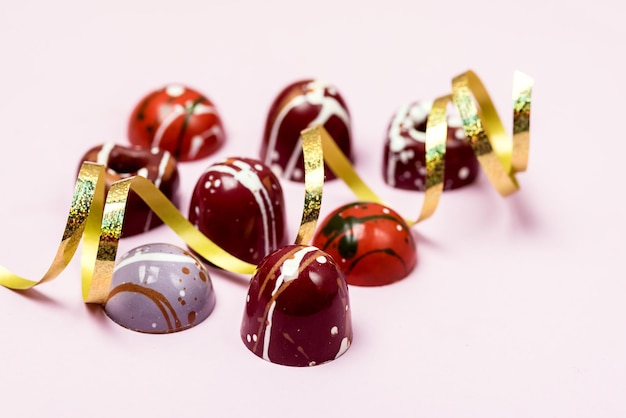 Bombones de lujo pintados con diferentes colores sobre fondo rosa Hermosa y exclusiva Caramelo de chocolate hecho a mano Horizontal