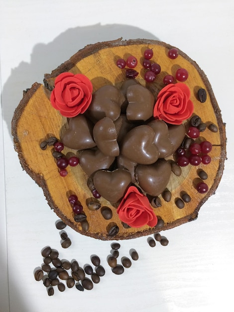 Bombons de chocolate apetitosos em um fundo branco Em um corte de madeira Com flores e grãos de café