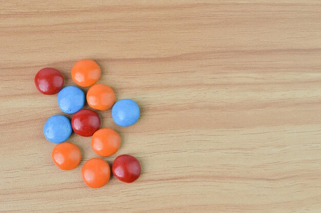 Bombons de chocolate coloridos sobre fundo de madeira