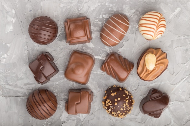 Bombons de chocolate diferentes sobre uma superfície de concreto cinza. vista do topo.