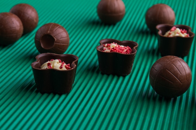 Foto bombons de chocolate doce marrom close-up sobre fundo verde. conceito de alimentos pouco saudáveis.