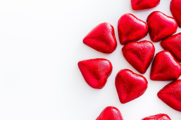 Bombons de chocolate em forma de coração embrulhados em papel alumínio vermelho para o dia dos namorados.